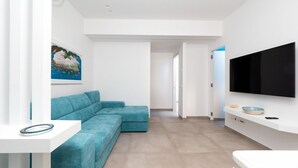 Ein modernes Wohnzimmer mit einem salbeigreenfarbenen Ecksofa, einem Flachbildfernseher an der Wand und einem Gemälde.