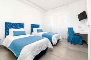 Een hotelkamer met twee bedden, een bureau, een stoel en een televisie.