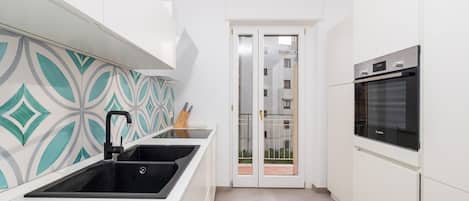 Cozinha moderna com pia preta, armários brancos e forno Bosch.