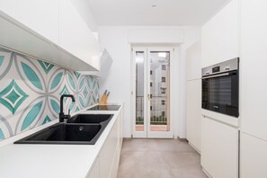 Eine moderne Küche mit einem schwarzen Spülbecken, weißen Schränken und einem Bosch-Ofen.