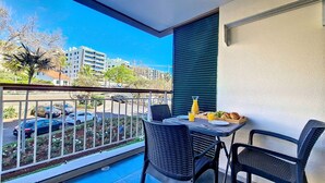 Un balcon avec deux chaises, une table et un plateau contenant de la nourriture et des boissons.