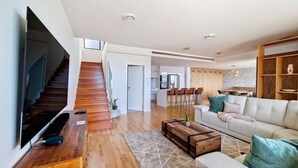 A modern living room with a staircase, a dining area, and a kitchen. - Allure Alannas Villa by LovelyStay (Funchal)