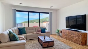 A modern living room with a beige sofa, a wooden coffee table, and a TV on a wooden cabinet. - Allure Alannas Villa by LovelyStay (Funchal)