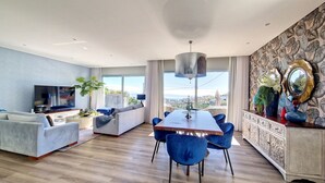 Una sala de estar moderna con comedor, televisor y balcón con vistas.