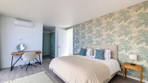 A bedroom with a bed, a desk, a chair, and a nightstand. - Ohana Ocean View by LovelyStay (Arco Da Calheta)