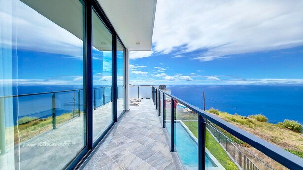 A balcony with a glass railing overlooking a coastal view. - Ohana Ocean View by LovelyStay (Arco Da Calheta)