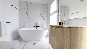 Une salle de bain moderne avec une baignoire sur pieds, un meuble-lavabo en bois et un grand miroir.