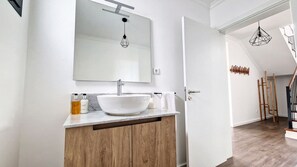 Ein modernes Badezimmer mit Waschbecken, Holzschrank und großem Spiegel.