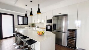 A modern kitchen with white cabinets, stainless steel appliances, and black pendant lights. - Costa Vista by LovelyStay (Funchal)