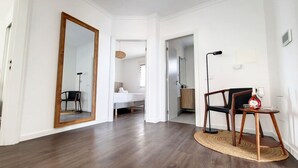 A modern hotel room with a large mirror, a wooden floor, a round woven rug, and a small table with a bottle and glass. - Costa Vista by LovelyStay (Funchal)