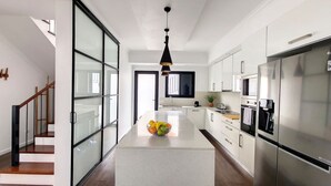 A modern kitchen with a central island, stainless steel appliances, and a glass partition wall. - Costa Vista by LovelyStay (Funchal)