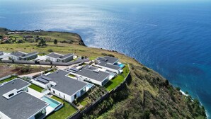 Un quartier résidentiel en bord de mer, avec des maisons modernes, une piscine et une vue sur la mer.