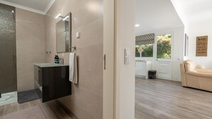 Une salle de bain moderne avec une douche à parois de verre, un meuble-lavabo avec un miroir et une serviette accrochée au mur.
