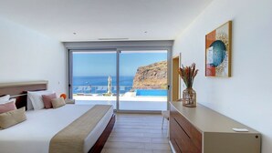 Et moderne hotelværelse med en stor seng, et skrivebord og udsigt over havet.