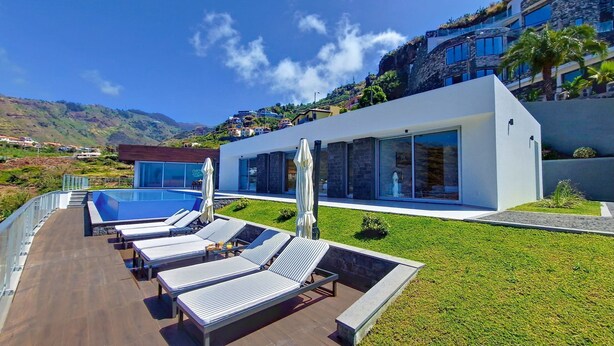 Et moderne resort med pool, liggestole og udsigt over de omkringliggende bakker.