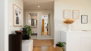 A modern interior with a wooden bench, a white sofa, a plant, and framed artwork on the wall.