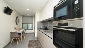 A modern kitchen with a Bosch microwave, oven, and coffee maker, a dining area with a table and chairs, and a clock on the wall.
