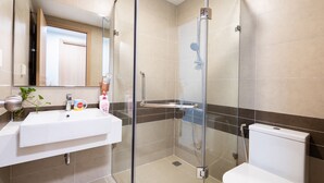 A modern bathroom with a glass-enclosed shower, a white sink, and a toilet. - Helios Rivergate Apartment (Ho Chi Minh City)