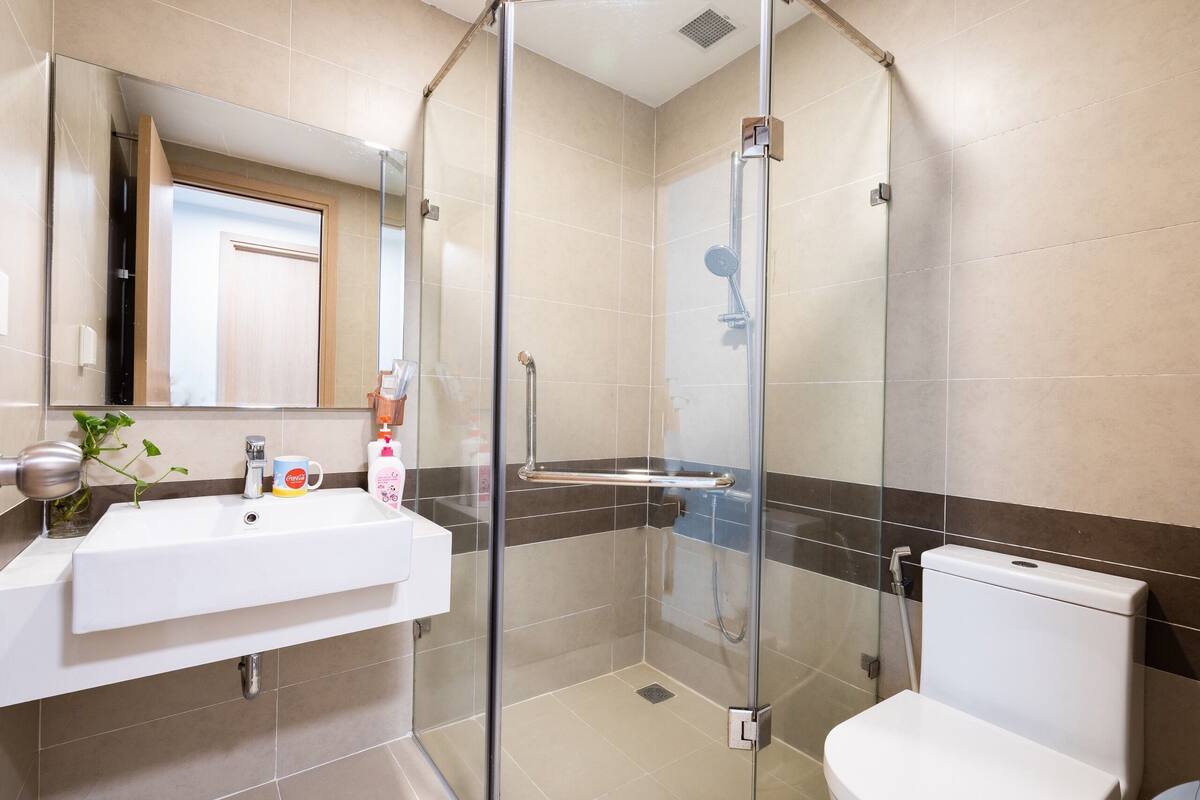 A modern bathroom with a glass-enclosed shower, a white sink, and a toilet.