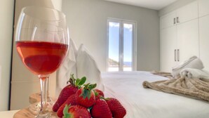 Ein Schlafzimmer mit einem Bett, einem Glas Rotwein und Erdbeeren.