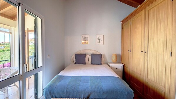 Un dormitorio con cama, mesita de noche, armario y una obra de arte en la pared.