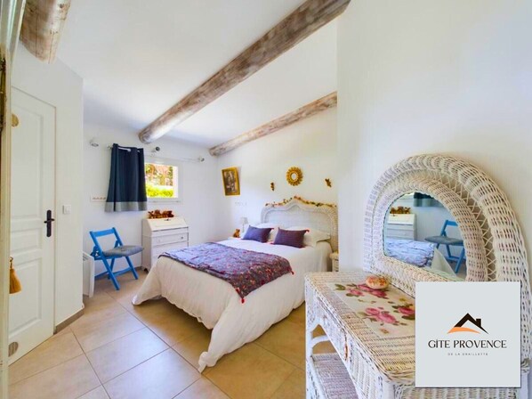 A bedroom with a bed, a chair, a dresser, a window, and a mirror. - Gîte de la Draillette (Noves)