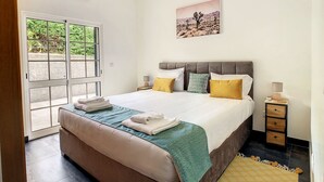 Une chambre à coucher comprenant un lit, des tables de chevet, une fenêtre et un appareil de climatisation.