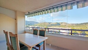 Een balkon met een tafel en stoelen, met uitzicht op een bergachtig landschap.