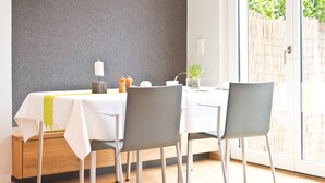 Un coin repas avec une table mise pour deux, une bougie et une petite plante posée sur la table.