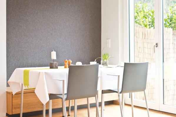 Un comedor con una mesa lista para dos personas, una vela y una pequeña planta encima.
