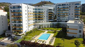 A modern multi-story hotel with a central courtyard featuring a swimming pool, outdoor seating, and greenery.