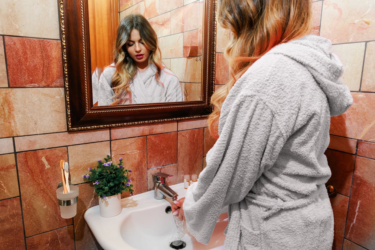 A bathroom with a sink, mirror, and toiletries.