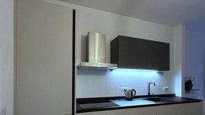 A modern kitchen with white cabinets, a black countertop, and a stainless steel range hood. - Cozy apartment near the center, excellent for families (Bardolino)