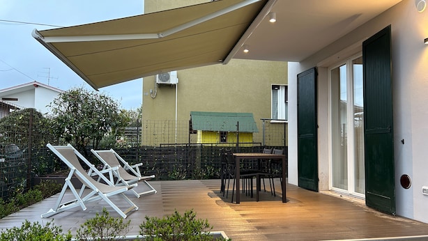 A patio with a table and chairs, a covered area, and a stone pathway. - Cozy apartment near the center, excellent for families (Bardolino)