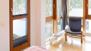 A room with large windows, a radiator, a chair, and a bed. - Beautiful apartment for 4 guests with WIFI, TV and balcony (Greifswald)