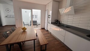 A modern kitchen with a wooden dining table, a built-in oven, and a large window. - El Balcón          . (Algodonales)