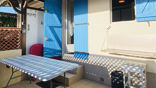 Een terras buiten met een tafel, stoelen en een afvalbak.