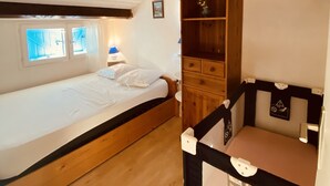 Een slaapkamer met een enkel bed, een houten garderobe en een klein bureau.