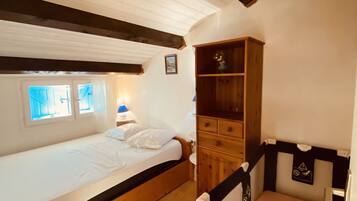 Une chambre avec un lit simple, une armoire en bois et un petit coin bureau.