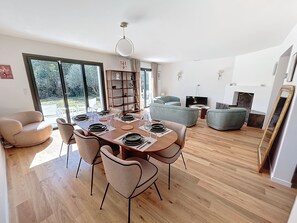 Enjoy meals with family and friends at the spacious dining table, surrounded by comfortable seating and a stylish shelving unit.
