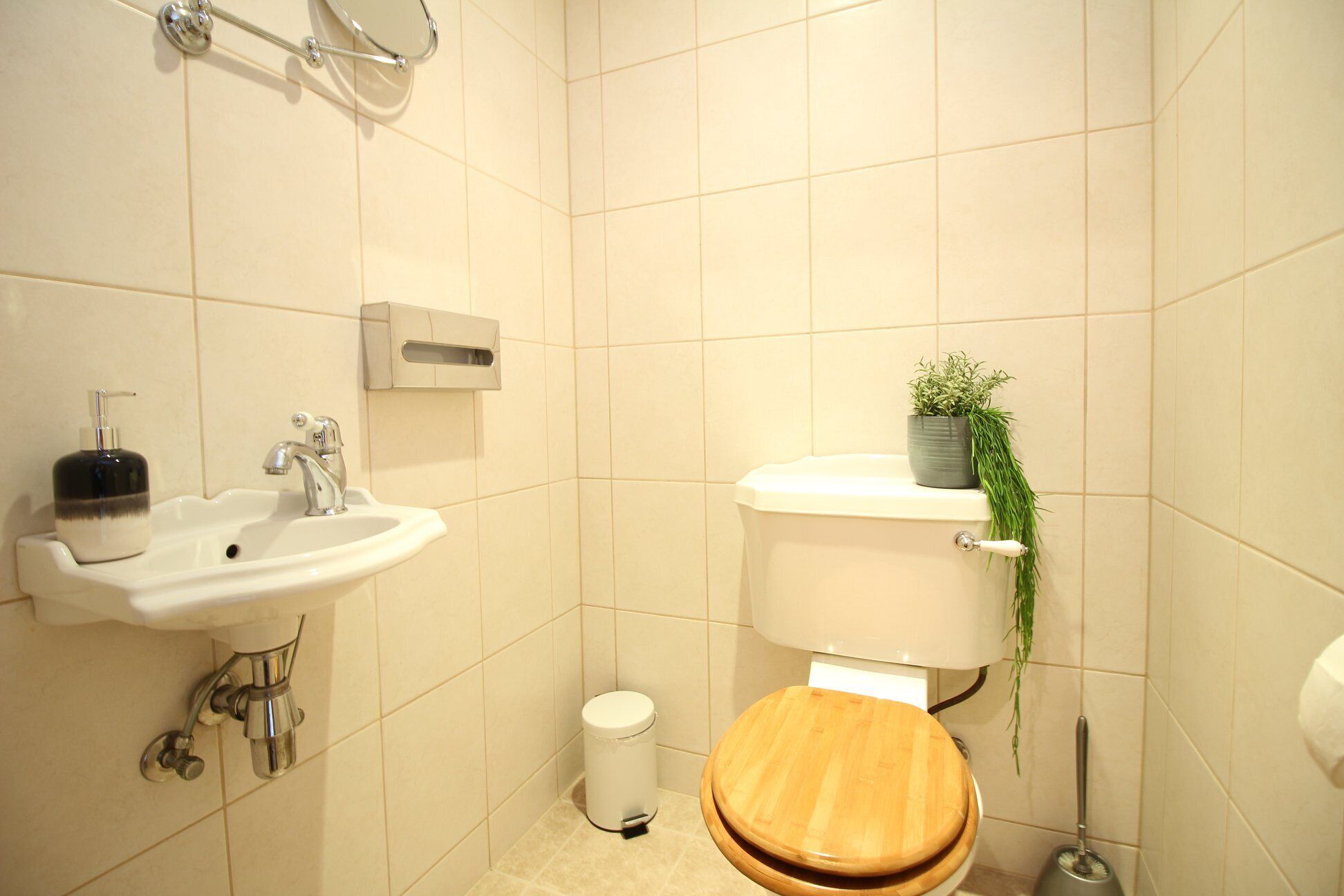 Une salle de bain avec un lavabo blanc, des toilettes et une petite poubelle.