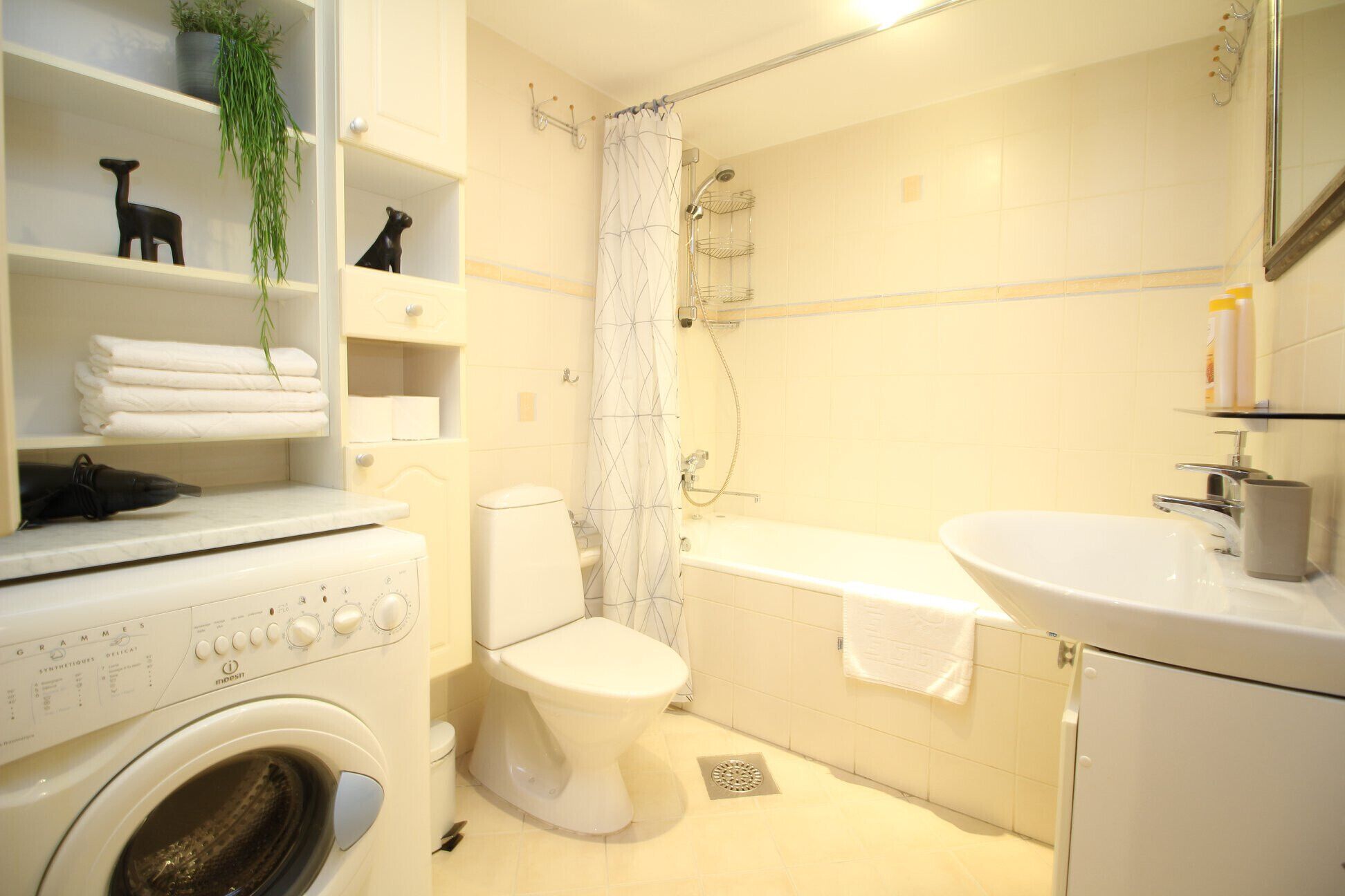 A compact bathroom with a washing machine, toilet, bathtub, and a sink.