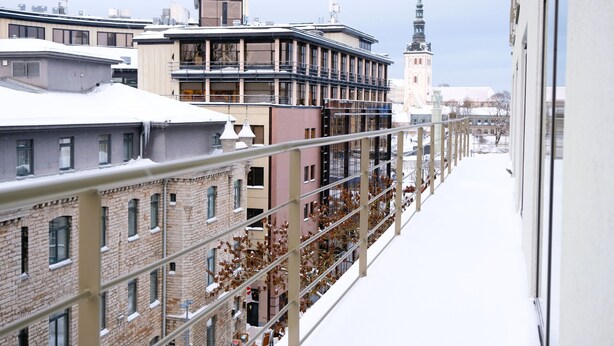 A snow-covered urban street with historic buildings and a prominent church tower. - Tallinn City Apartments Roosikrantsi (Tallinn)