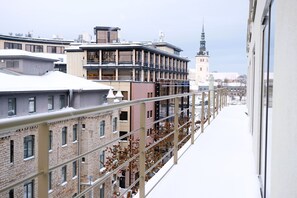 A snow-covered urban street with historic buildings and a prominent church tower. - Tallinn City Apartments Roosikrantsi (Tallinn)