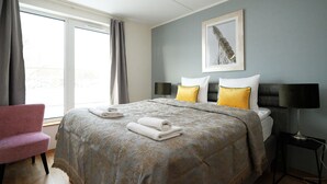 A hotel room with a bed, a chair, a bedside table, a lamp, and a window with curtains. - Tallinn City Apartments Roosikrantsi (Tallinn)