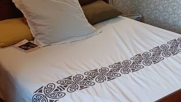 A bedroom with a bed, pillows, a nightstand, and a wall-mounted lamp.