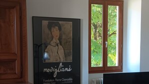 A dining area with a round table covered in a white tablecloth, a wooden cabinet, and a framed picture on the wall. - lac D'annecy Dans Maison de Charme (Doussard)