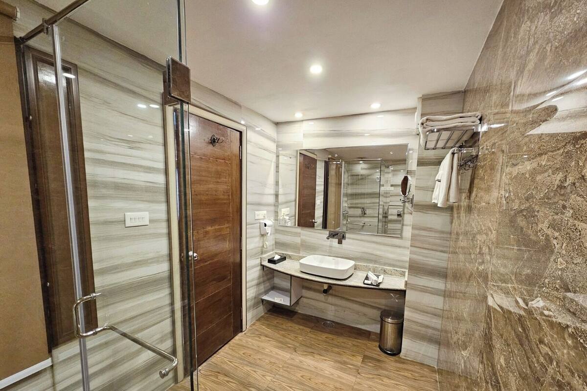 A modern bathroom with a glass shower enclosure, a vanity with a sink, and a mirror.