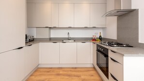 A modern kitchen with white cabinets, a stainless steel range hood, a built-in oven, and a granite countertop.
