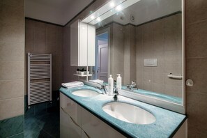 A modern bathroom with two sinks, a towel rack, and a mirror. - Florissa (Blevio)
